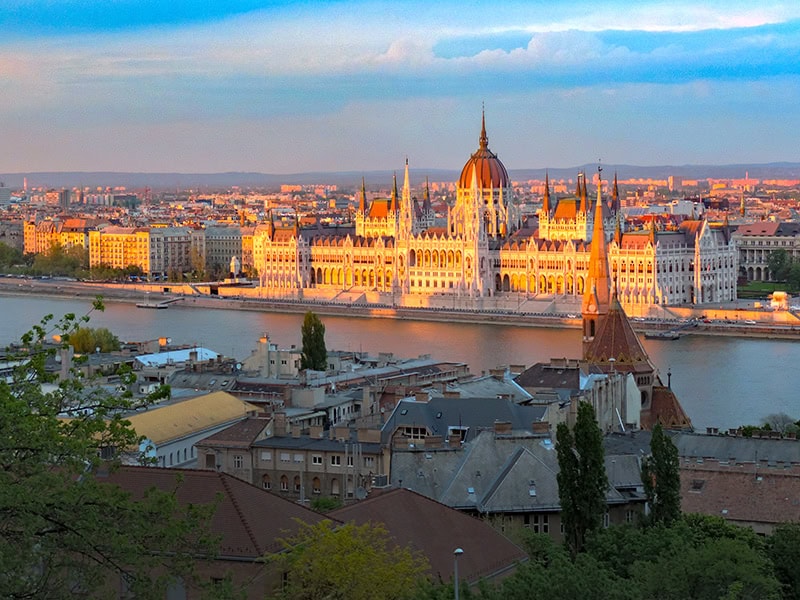 a parliament building at sunset, seen on a Eastern Europe river cruise