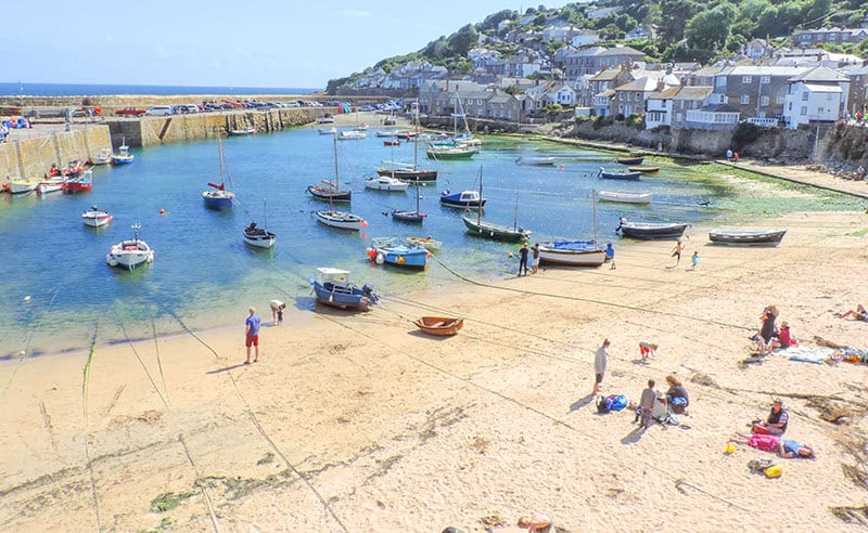 a small harbor with boats and people on the beach