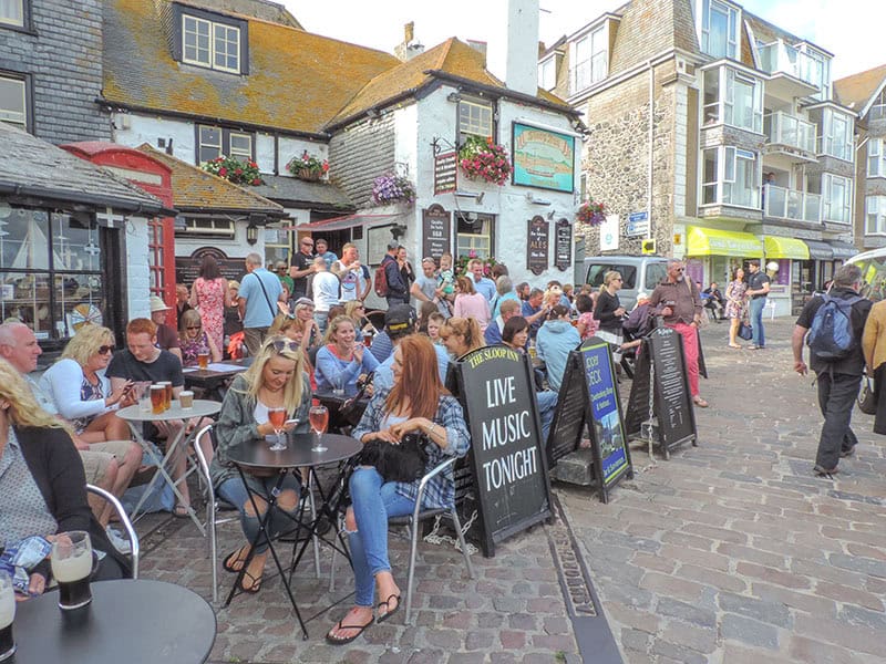 a crowd of people sitting at outdoor tables having drinks