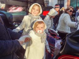 2 small girls dressed in white jackets on a horse draw carriage