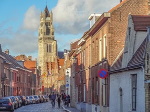 a street with parked cars by a large church steeple