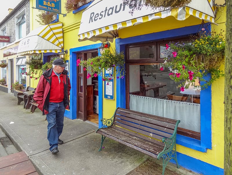 man walking past a restaurant painted yellow