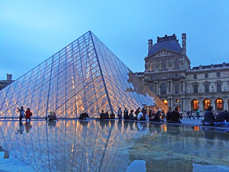 people seated by a glass pyramid - 2 days in Paris