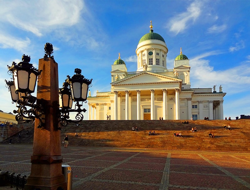 People walking into a large white church on a plaza, one of the things to do in Helsinki