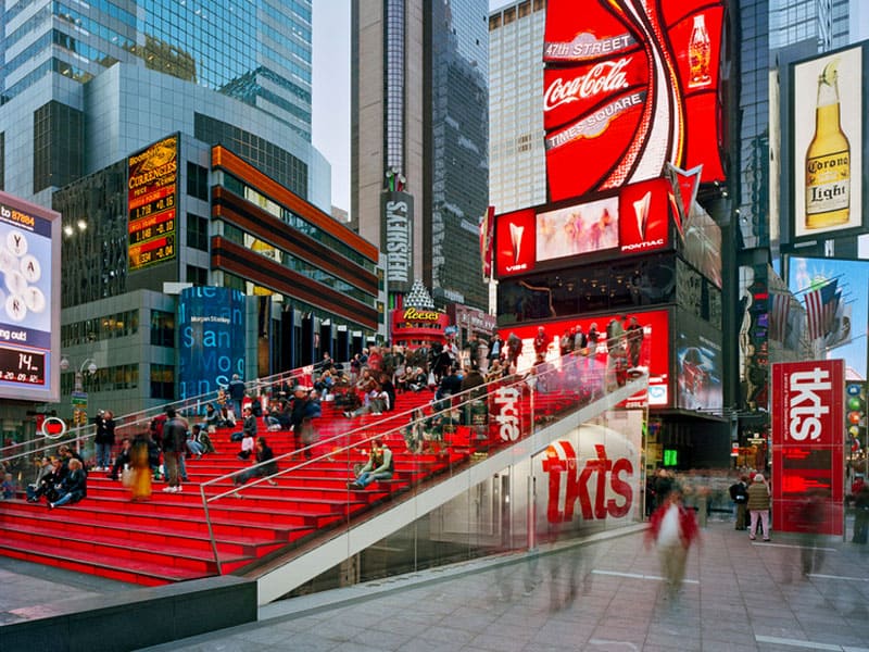people on a bright red staircase near a ticket booth in New York
