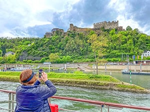 a woman taking a photo of a castle on a hilltop