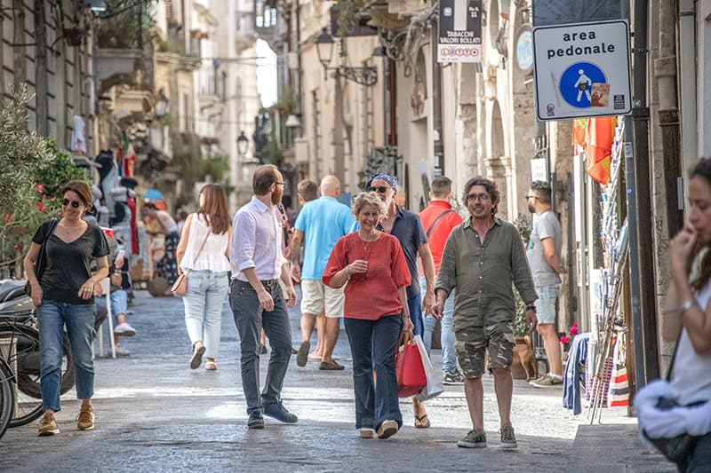 people walking through an old Italian city while seeing Sicily by car