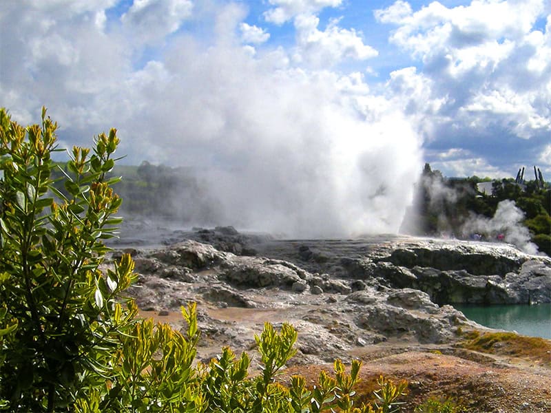 a geyser erupting in an area of rocks
