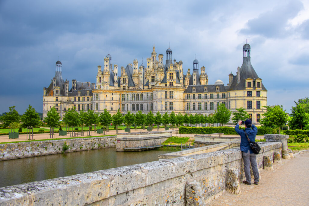 a man taking a photo of a large chateau