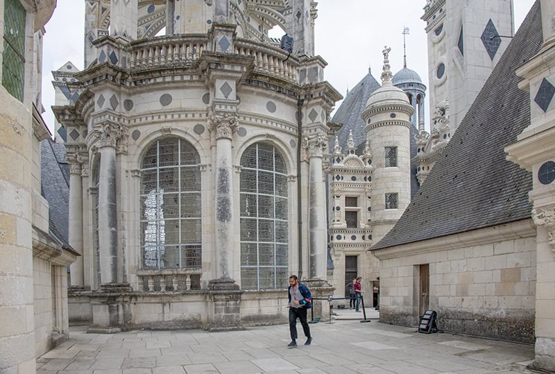 people walking on the ornate rooof of a chateau