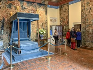 people looking at a blue-colored bed in in a chateau in the Loire Valley