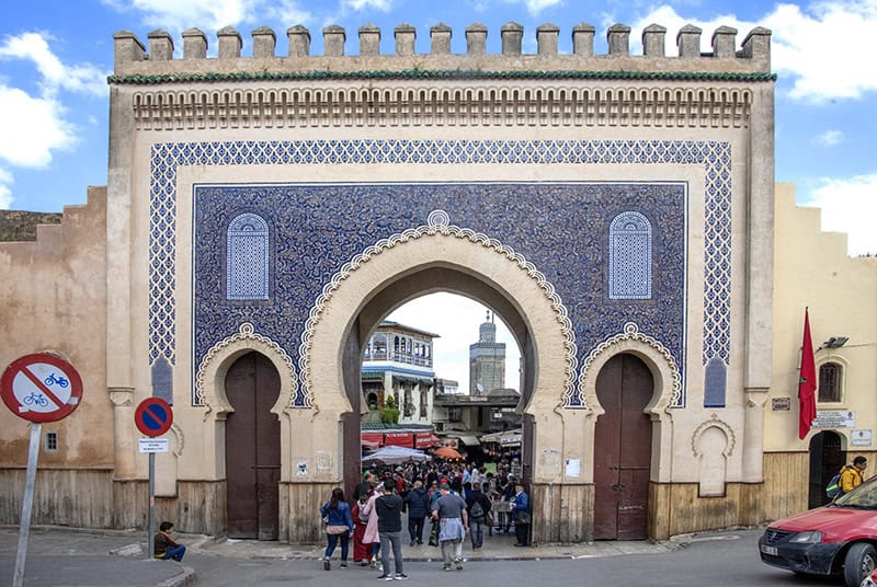 people walking through an ancient blue city gate