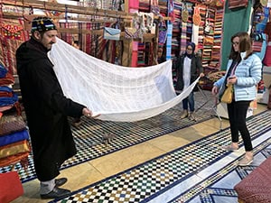 people holding a large piece of white cloth in the market in Fez Morocco