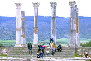 people sitting on steps in front of tall Roman columns