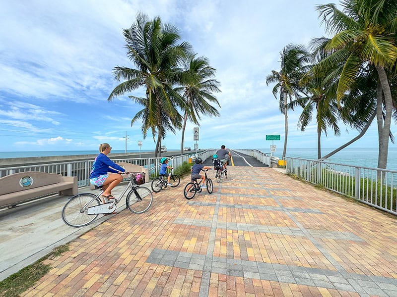 a family bicycling across a causeway