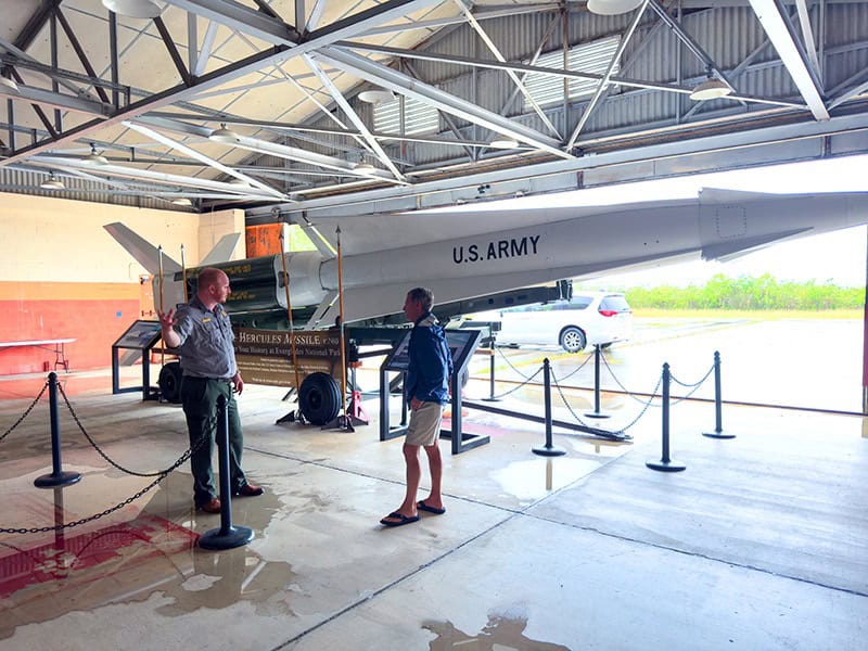 a park ranger and a visitor standing near a missile in the Everglades National Park