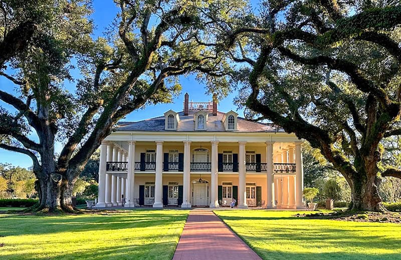 a beautiful southern mansion framed by large oak trees