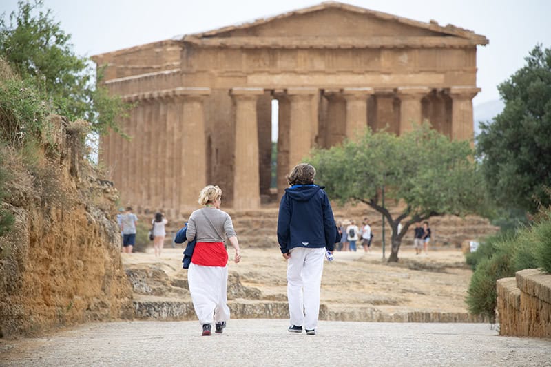 two young women strolling towards an ancient Greek temple in Agrigento Sicily