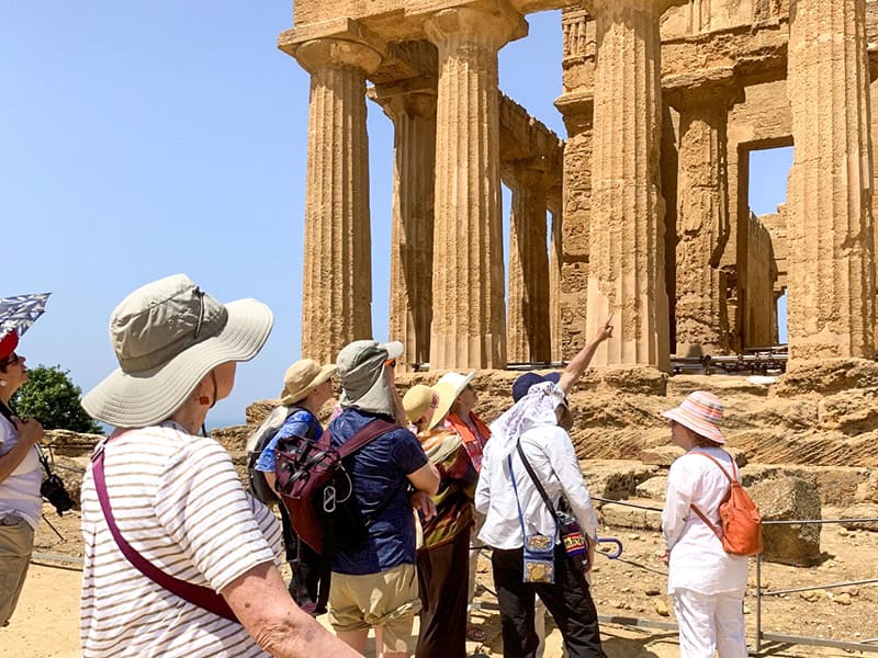 a guide with a group of tourists pointing at a temple