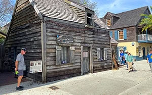 people walking by an old wooden schoolhouse