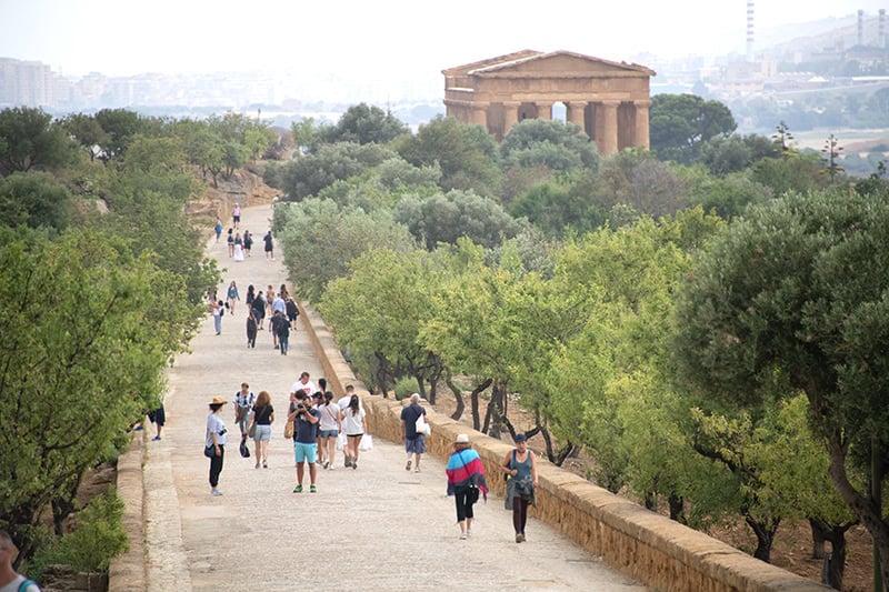 people of a walkway passing a temple in Agrigento Sicily