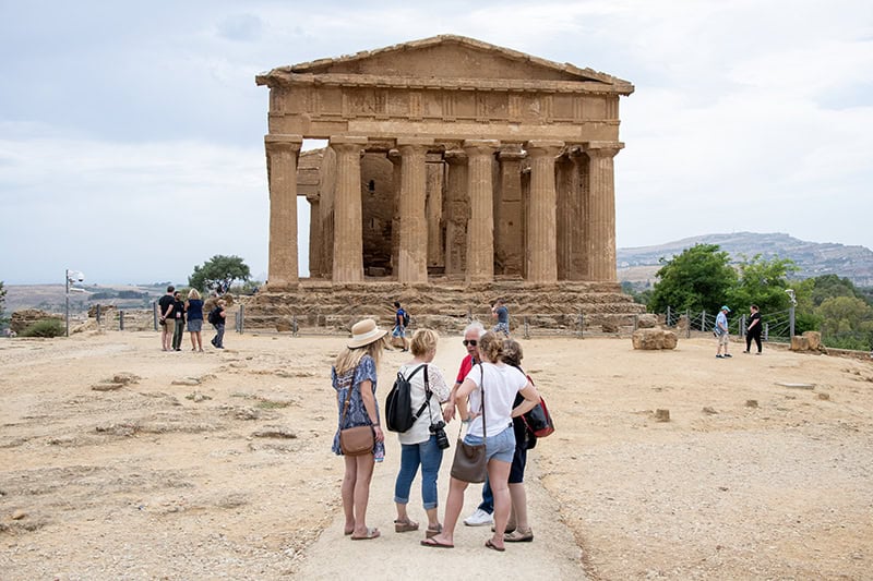 A tour guide talking with young women about the Temple of Concordia in Agrigento Sicily